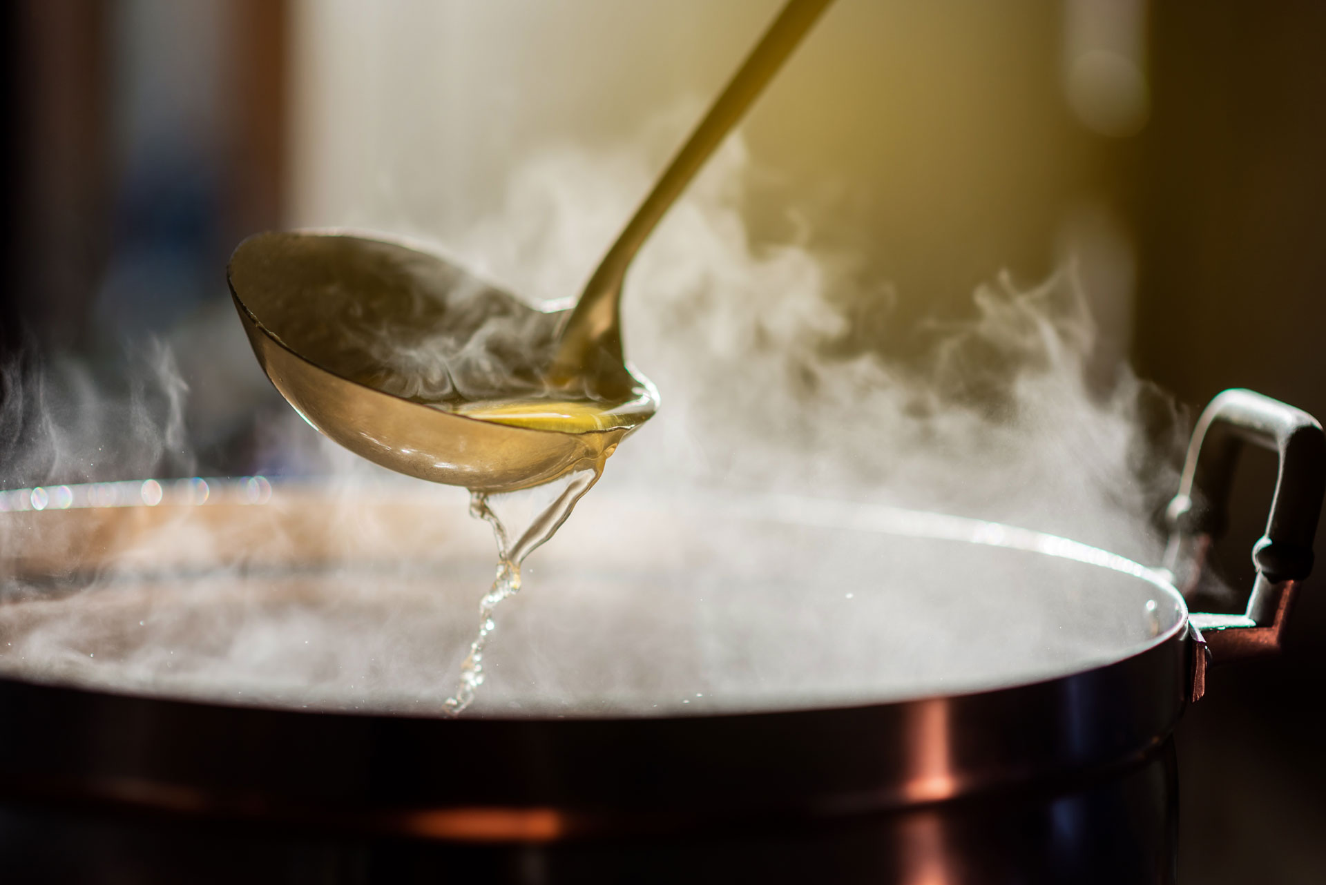 A photo of a soup being poured with a large spoon.